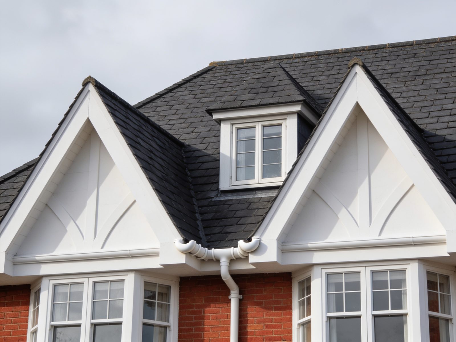 A newly tiled roof over two gables and a dormer window, with crisp white bargeboards and clean guttering.
